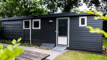 Une petite cabane à un seul étage, à l’extérieur sombre, avec une porte d’entrée et deux fenêtres.