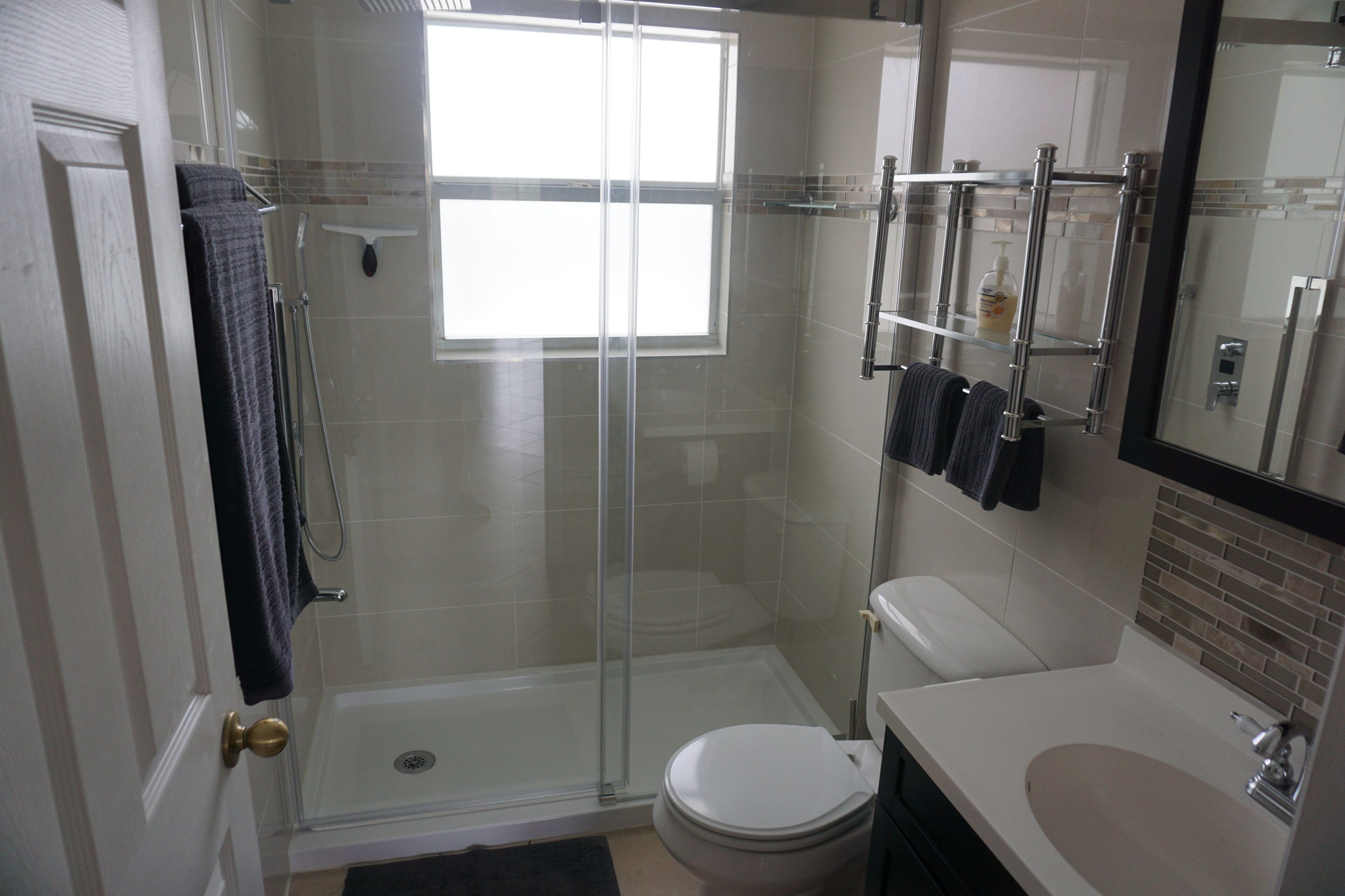 A modern bathroom with a glass shower enclosure, a toilet, and a sink.