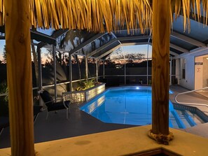 A pool area with a covered seating area and a view of the surrounding landscape. - Villa with solar and electrically heated pool,  south-facing exposure. (Cape Coral)