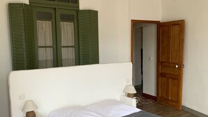 A bedroom with a single bed, a wooden ceiling beam, a green shuttered window, and a wooden door. - Character house, Mas du 17è,quiet,private pool 9x4,5m,air-conditioned,near Uzes (Le Pin)
