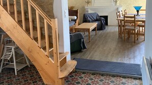 A spacious living area with a wooden staircase, a fireplace, and a dining area with wooden furniture. - Character house, Mas du 17è,quiet,private pool 9x4,5m,air-conditioned,near Uzes (Le Pin)