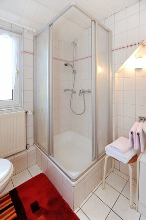 A bathroom with a shower, toilet, and a towel rack. - Apartment - Ferienhaus Zur Schmiede (Dunum)