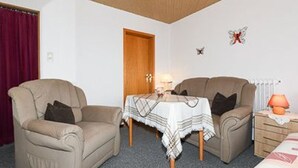 A room with two sofas, a small table with a tablecloth, a lamp, and a radiator.