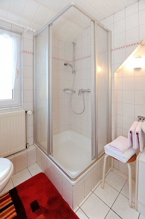 Une salle de bain avec une douche, des toilettes et un porte-serviettes.
