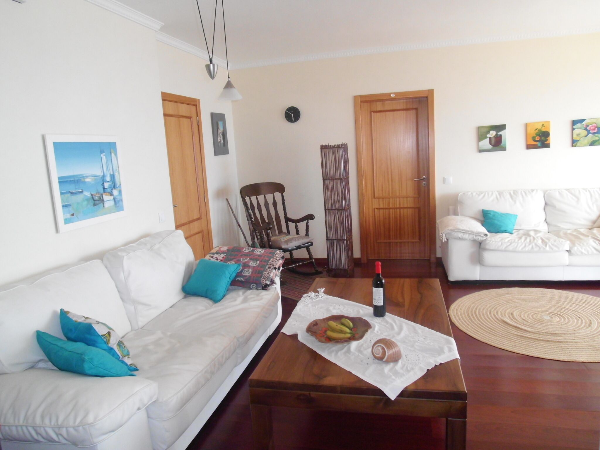 Ein Wohnzimmer mit einem weißen Sofa, einem Couchtisch mit Speisen, einem Sessel und einer weißen Couch.