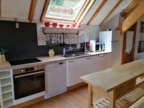 A compact kitchen with white cabinetry, a built-in oven, a dishwasher, a coffee maker, and a microwave.