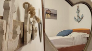 Een kamer met een bed, een spiegel in hartvorm die het bed reflecteert, een wanddecoratie en nautische decoratie, waaronder een touw en een anker.