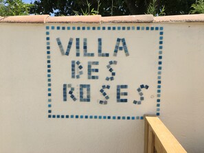 Pared com o texto "VILLA DES ROSES" em padrão de mosaico.