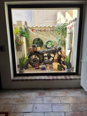 Ein Motorrad steht in einem Raum mit Fenster, Topfpflanzen und Heizkörper.