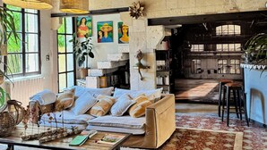 A spacious living area with a high ceiling, exposed wooden beams, a large sofa, a coffee table, and a fireplace. - ARLES Camargue, Character Arles House with Pool (Arles)