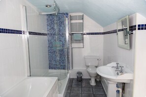 Une salle de bain avec une douche à parois de verre, une baignoire blanche, des toilettes blanches et un lavabo blanc.