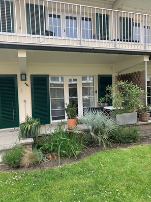 Ein Gebäude mit einem Balkon, grünen Fensterläden und Blumentöpfen.
