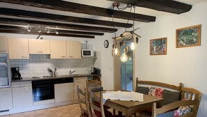 A kitchen with white cabinets, a microwave, and a sink. There is a dining table with chairs and a hanging light fixture. - Vacation on a farm - discover and experience nature (Baden-Württemberg)