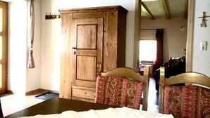 A room with a wooden cabinet, two patterned chairs, and a bed with a white bedspread. - Vacation on a farm - discover and experience nature (Baden-Württemberg)