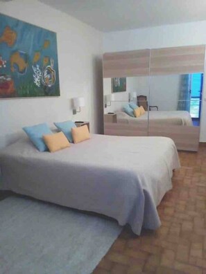 A bedroom with a bed, a nightstand, a mirror, and a painting on the wall. - Beachfront house with pool (Santa Cruz, Madeira)