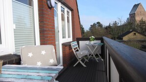 Eine Holzterrasse mit Tisch und Stühlen, einer Bank und einer Backsteinmauer.