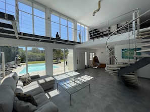 Un salón amplio con piscina, una escalera moderna y vistas al exterior.