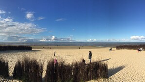 A beach with sand dunes, a clear sky, and a few people walking. - Renner Vacation Home Behind the Dike in Spieka-Neufeld, Including a Beach Chair (Wurster Nordseeküste)