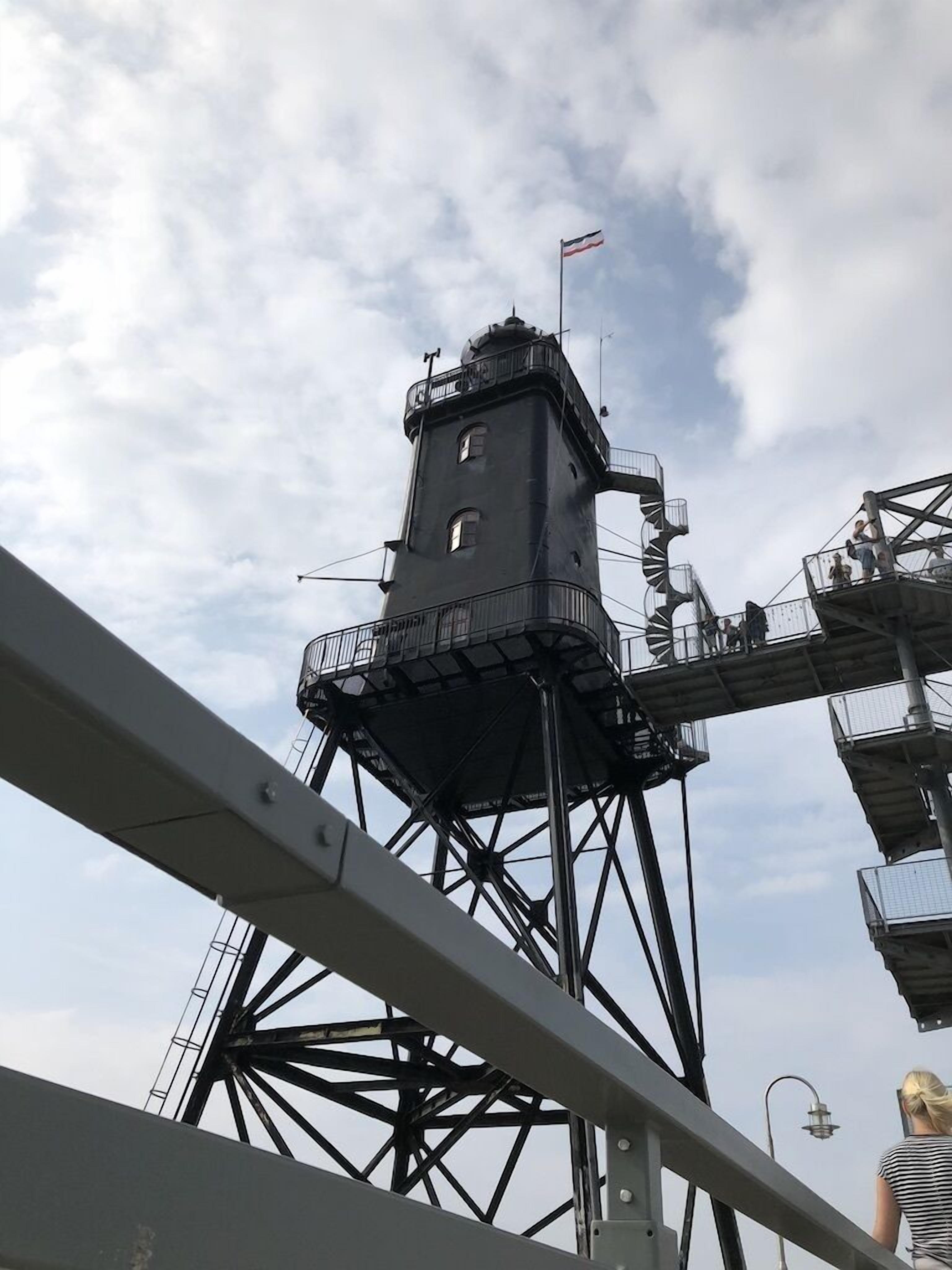 A tall, dark-colored tower with a flag, surrounded by a metal framework.
