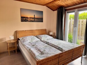Une chambre avec un lit, une table de chevet, une lampe et un tableau représentant un coucher de soleil.