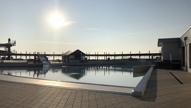 A swimming pool with a clear view of the surrounding buildings and a bridge in the background. - Renner Vacation Home Behind the Dike in Spieka-Neufeld, Including a Beach Chair (Wurster Nordseeküste)