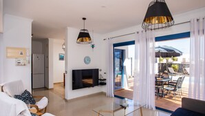 Un salon moderne avec un téléviseur, une table basse en verre et un espace salon.