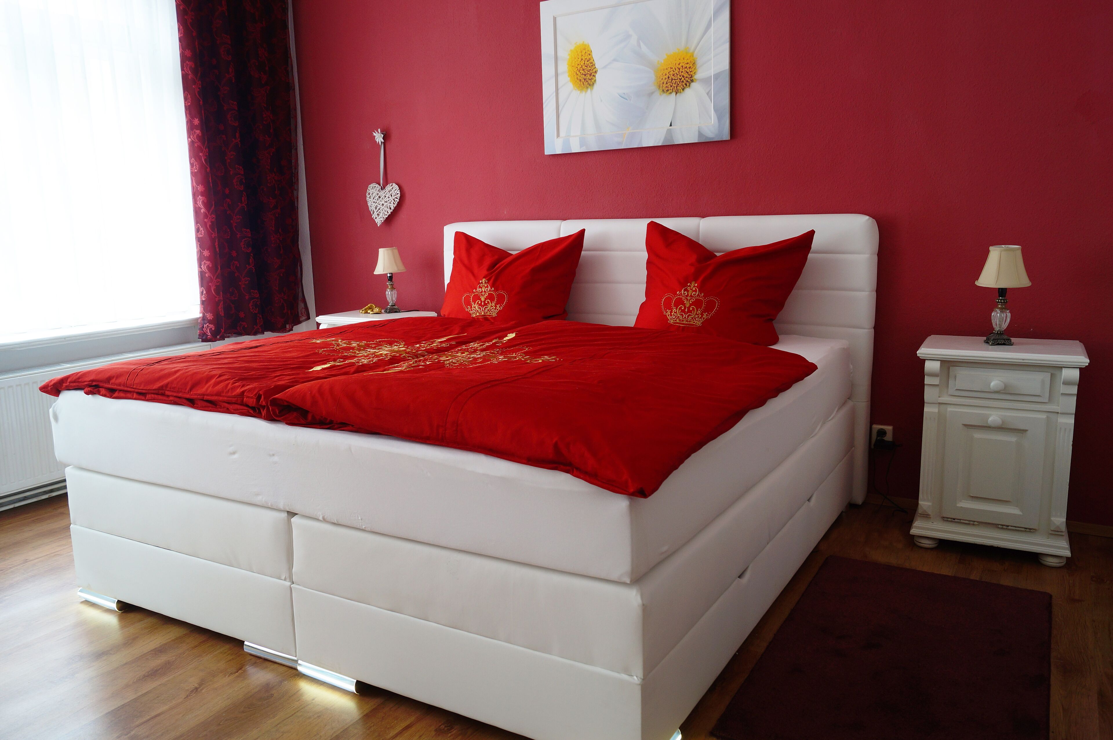 Une chambre à coucher avec un lit blanc, une literie rouge et un mur rouge.