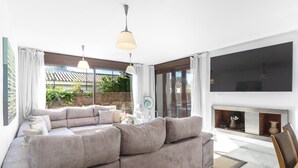 Un salon moderne doté d’un grand canapé d’angle, d’une cheminée et de grandes fenêtres donnant sur un jardin.