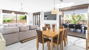 Un salon moderne avec un canapé, une table à manger et des chaises. On y trouve une cheminée et une vue sur l’extérieur.