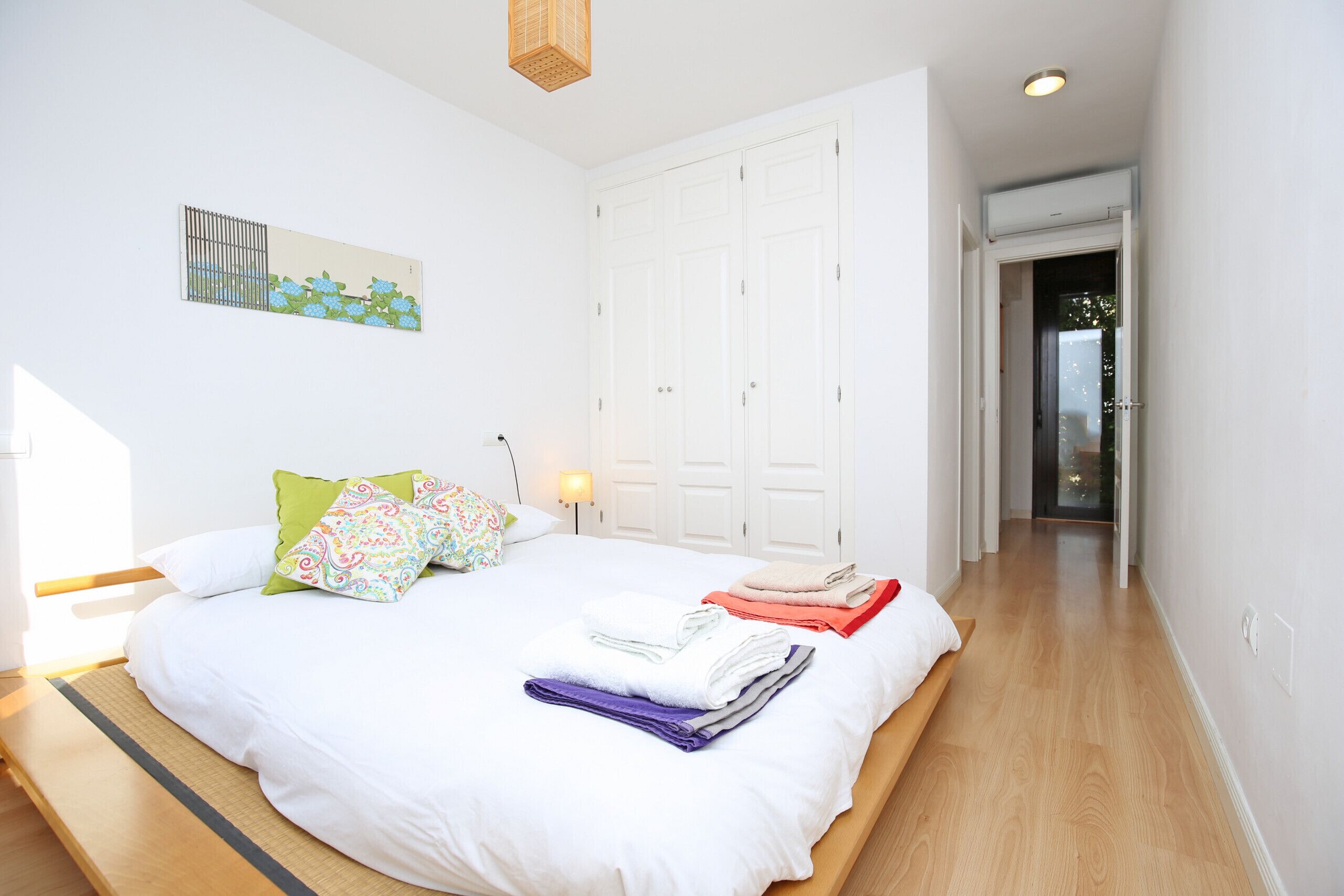 A bedroom with a bed, pillows, a nightstand, and a wardrobe.
