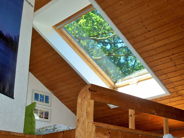 A room with a sloped wooden ceiling, a skylight, and a framed picture on the wall.