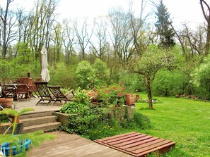 A wooden deck with outdoor furniture, surrounded by lush greenery and trees.