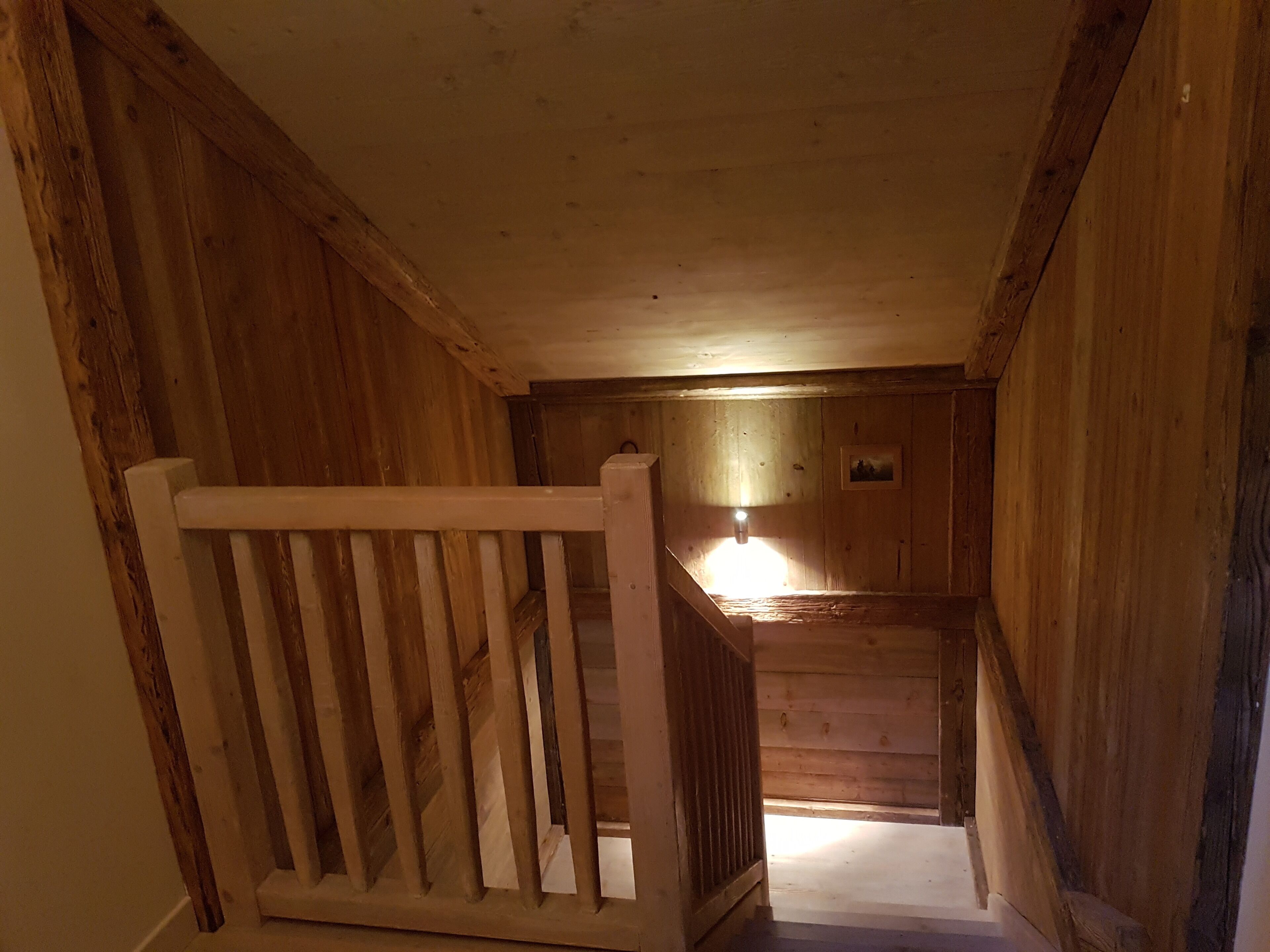 A wooden staircase with a railing leading to a landing.