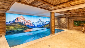 A modern indoor pool area with a large mural of a mountain landscape.