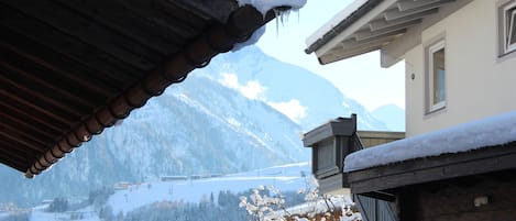 A mountain view with a wooden building and snow-covered roof.
