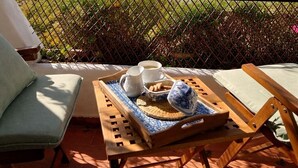 A terrace with a table set for two, a view of the sea, and a pergola with flowers.