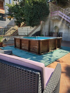 Un espace piscine agrémenté d’une table de billard en bois, de mobilier d’extérieur et d’un escalier menant à un niveau supérieur.