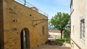 A stone building with a courtyard, a metal balcony, and a view of the landscape. - Locanda del podestà: 17th century mansion in Chianti (Montespertoli)