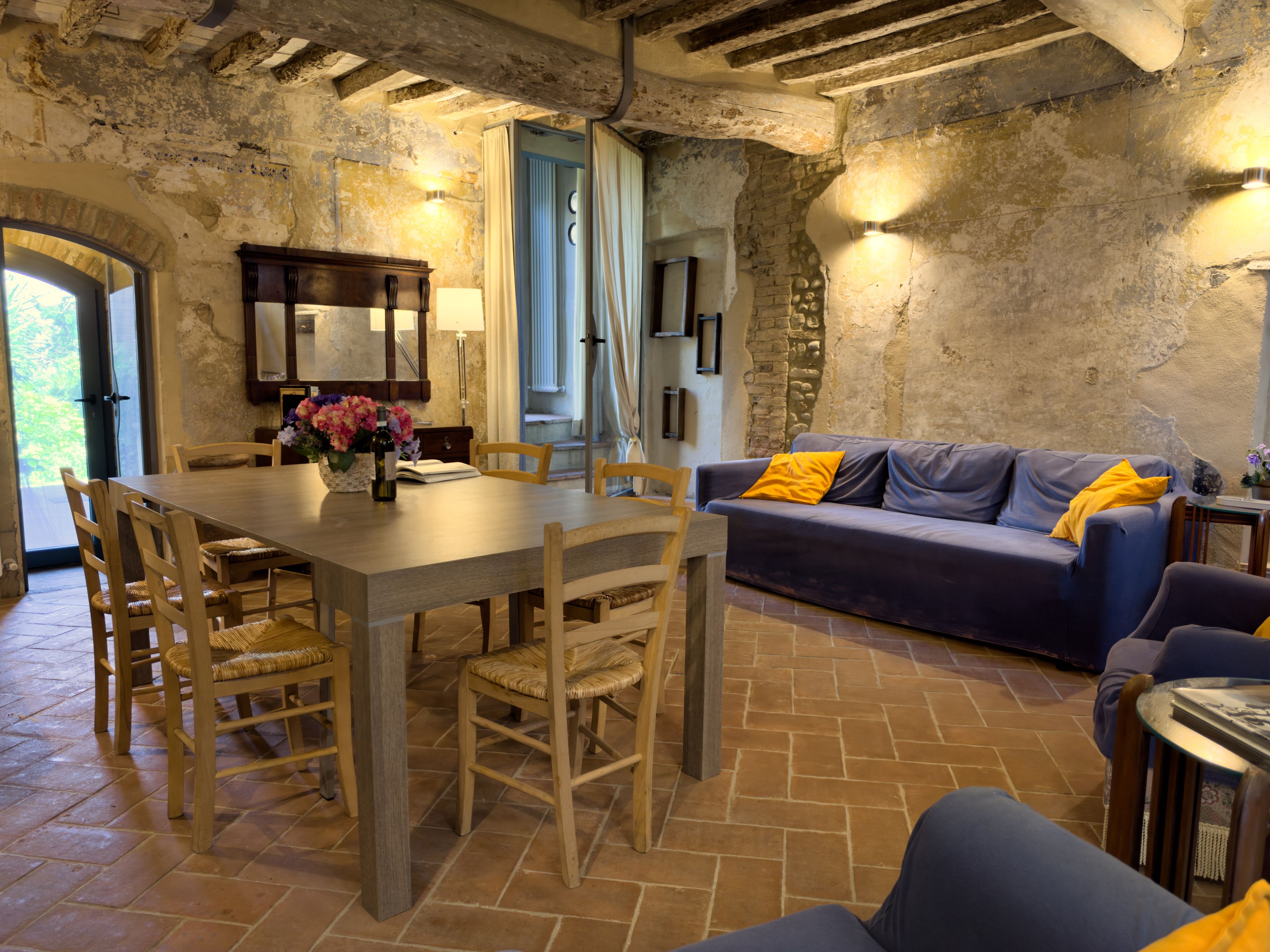 Un intérieur rustique comprenant un coin repas, un canapé et un mur en pierre.