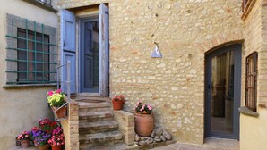 A stone building with a set of stone steps leading to a door, surrounded by potted plants. - Locanda del podestà: 17th century mansion in Chianti (Montespertoli)