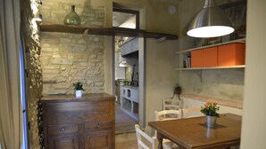 A rustic kitchen with a wooden island, white chairs, and a dining table. - Locanda del podestà: 17th century mansion in Chianti (Montespertoli)