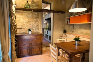 Une cuisine rustique avec des murs en briques apparentes, des meubles en bois et un coin repas comprenant une table et des chaises.