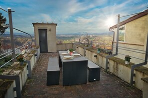 Une terrasse extérieure avec une table dressée pour deux personnes, offrant une vue sur un paysage magnifique.