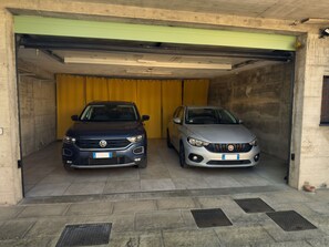 Deux voitures sont garées à l’intérieur d’un garage, derrière un rideau jaune et devant une porte verte.
