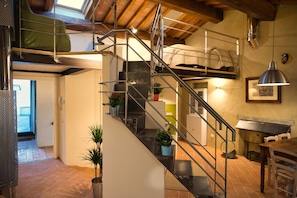 Un intérieur à plusieurs niveaux, avec un escalier, des rampes en métal, des plantes en pot et un coin repas.