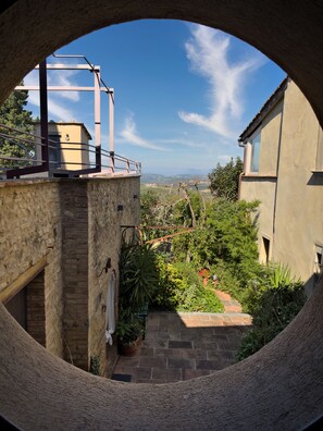 Une vue circulaire d’une cour intérieure avec un mur en pierre, une rambarde en métal et un pot de fleurs.