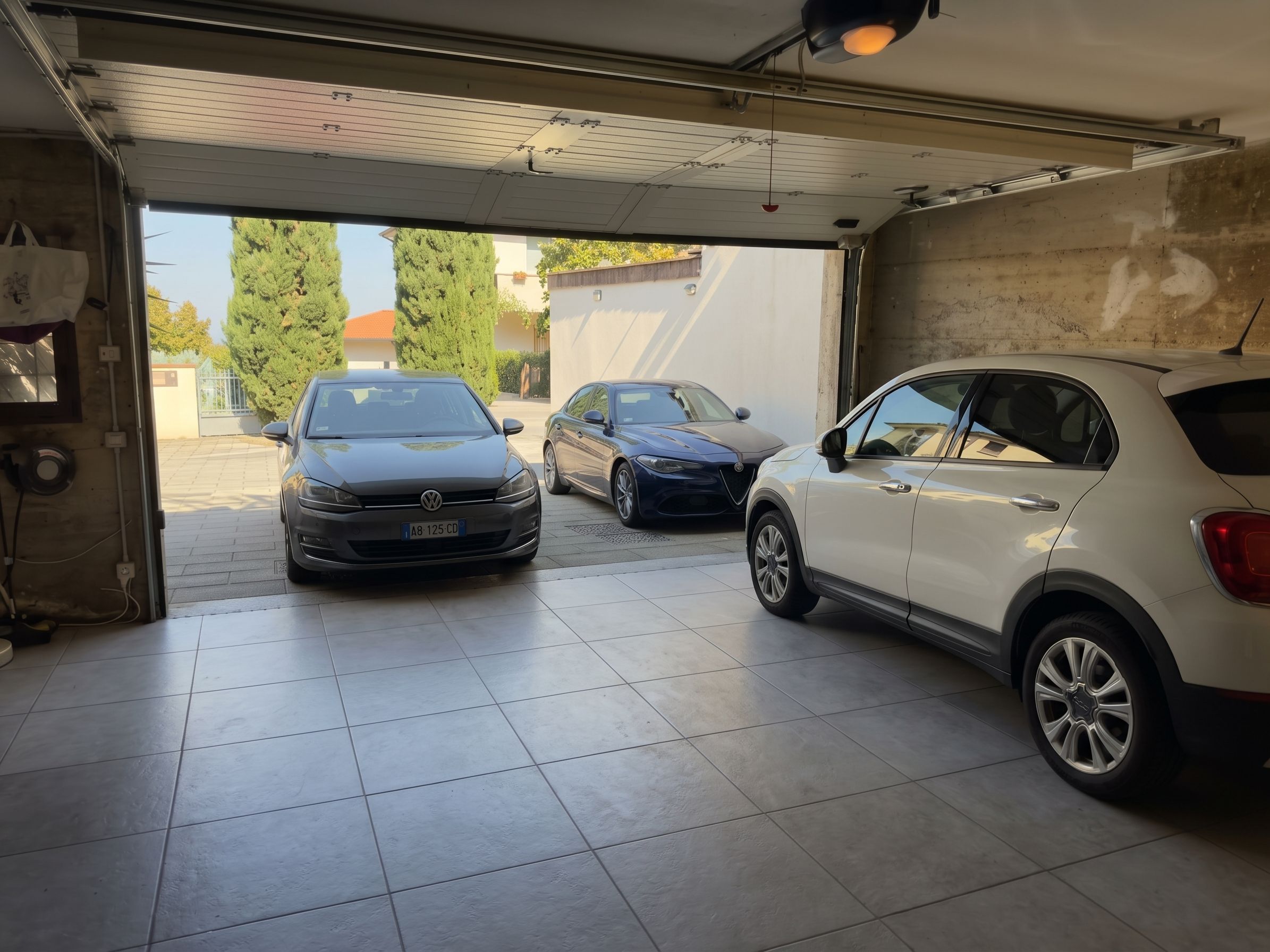 En garage med tre biler parkeret indeni.