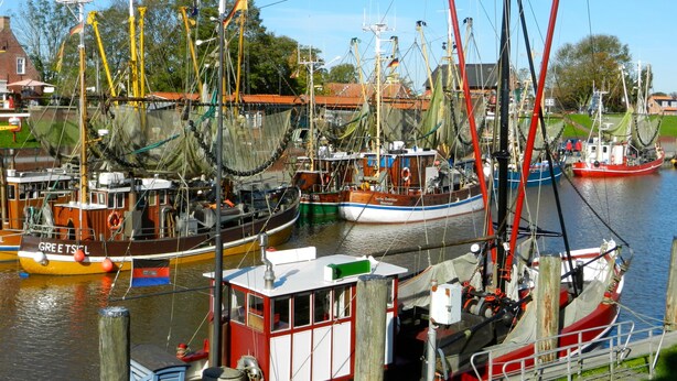 A harbor with multiple boats docked, including a prominent red boat named "Greetsiel". - Ferienhaus Seehund on the East Frisian North Sea coast with 3 bedrooms (Hamswehrum)