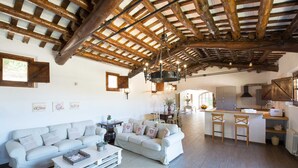 A spacious living area with a high wooden ceiling, a white sofa set, a coffee table, and a kitchen area with a bar. - House with pool, 20.000 m2 garden, ping-pong close to the beach for 18 people (Sant Andreu de Llavaneres)