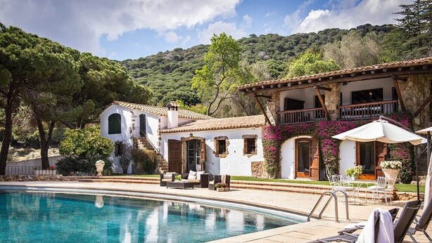 A poolside area with a clear pool, lounge chairs, and a building with stone walls and a balcony. - House with pool, 20.000 m2 garden, ping-pong close to the beach for 18 people (Sant Andreu de Llavaneres)